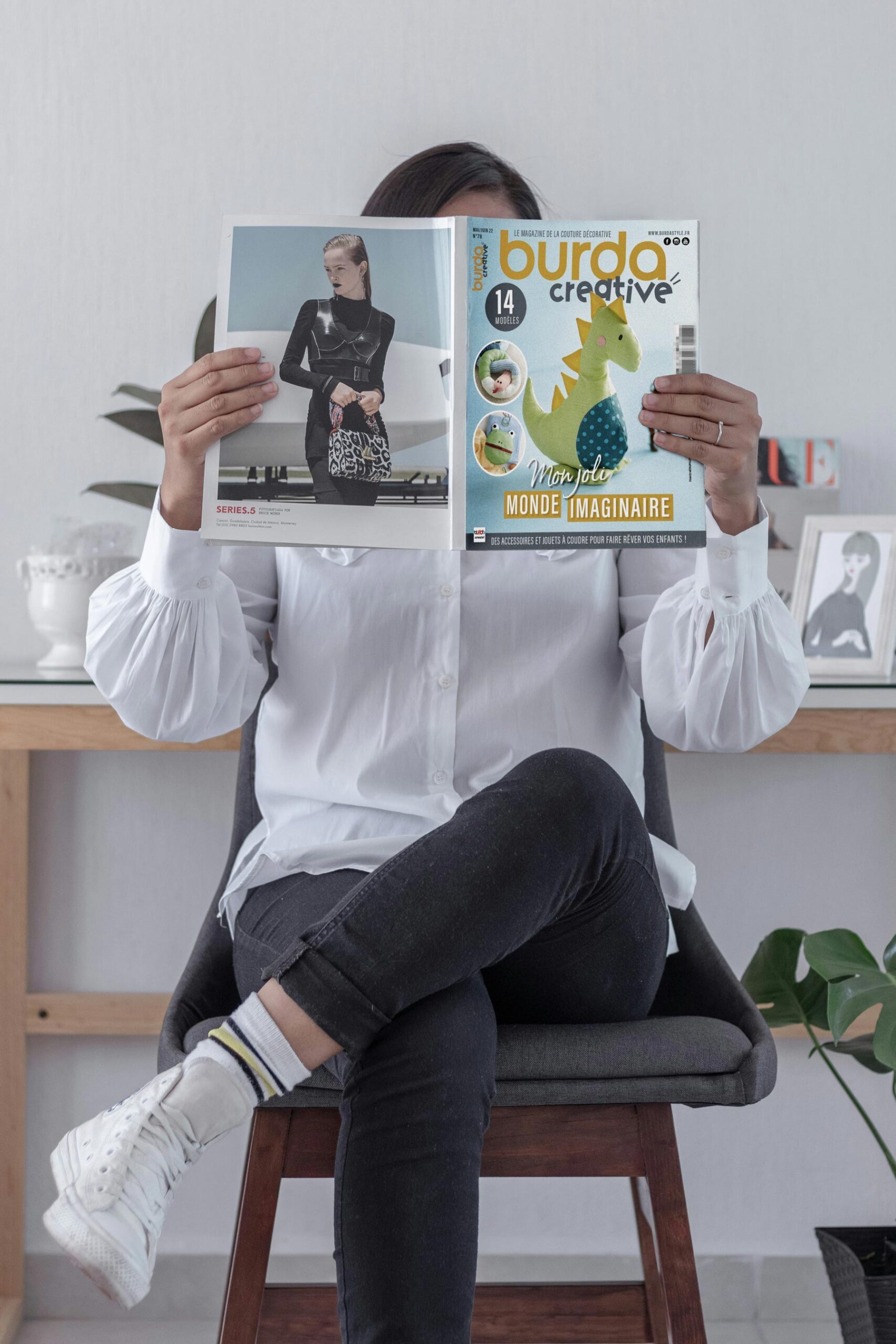 Personne lisant le magazine Burda Creative, mettant en avant la couverture et le logo d'un magazine de couture moderne.