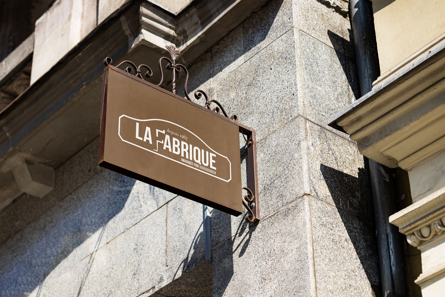 Création de logo pour imprimerie : enseigne murale avec le logo La Fabrique sur un panneau métallique extérieur.