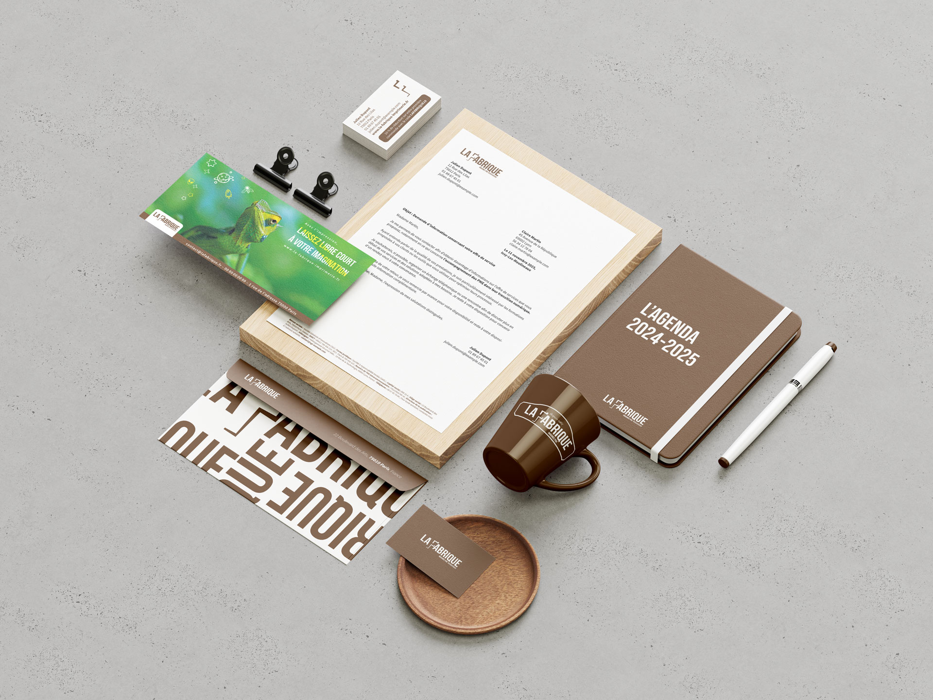 Ensemble de papeterie et accessoires de bureau aux couleurs de l’imprimerie La Fabrique, incluant un carnet, une tasse et des cartes de visite.